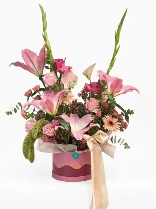 Centro de flor natural rosa con liliums, rosas, gerbera y gladiolos en sombrerera rosa con lazo